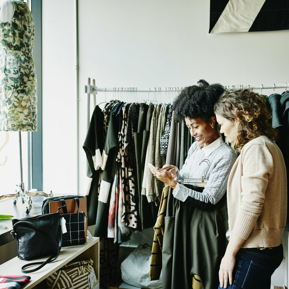 Woman showing shop owner photos on smartphone